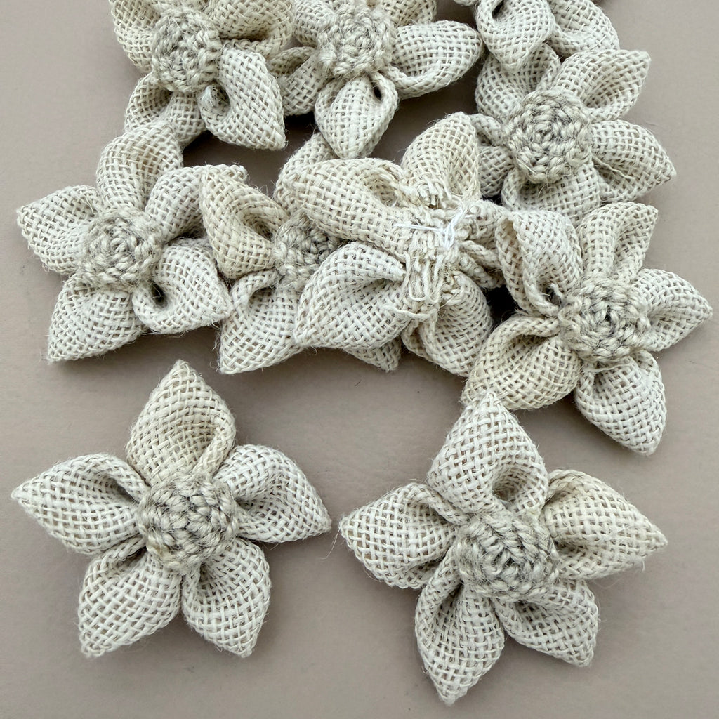 Pack of natural white jute burlap flower patches spread on grey background