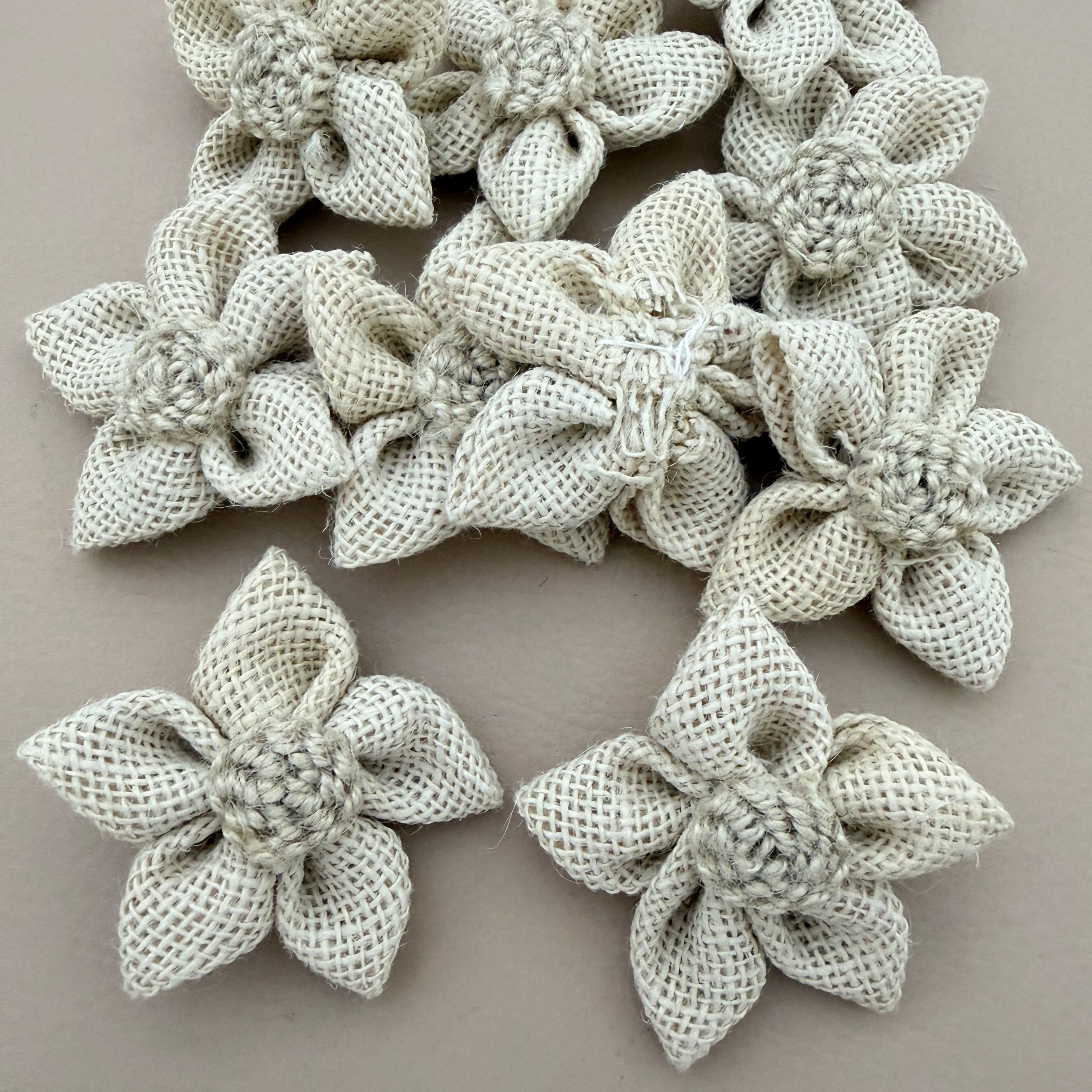 Pack of natural white jute burlap flower patches spread on grey background