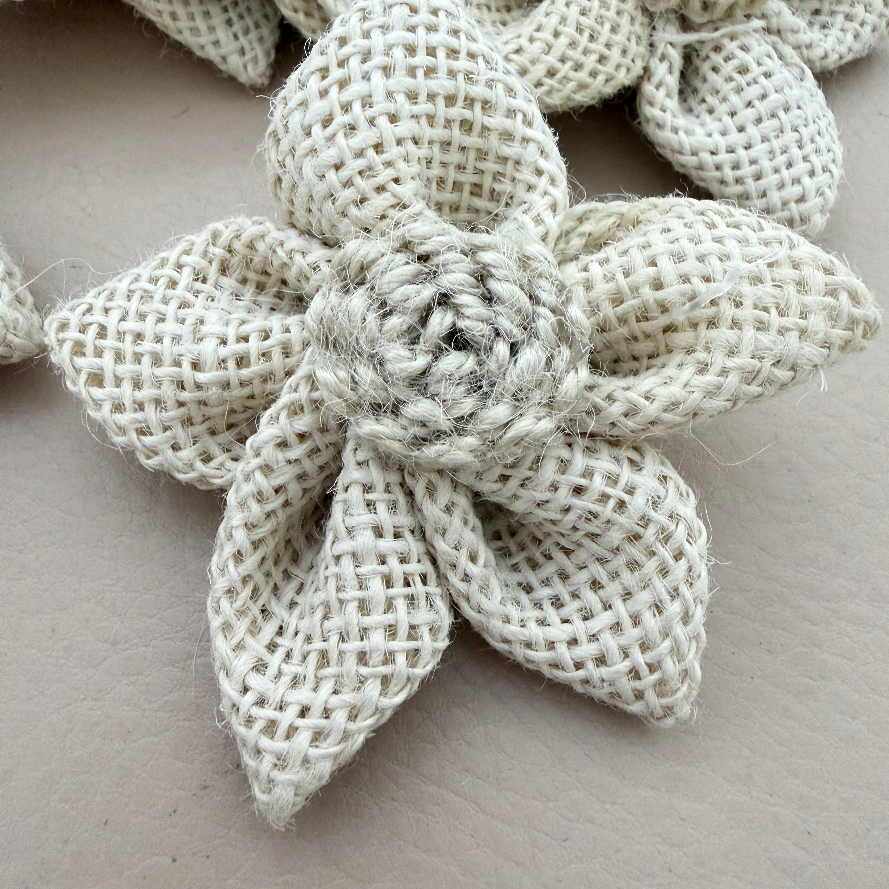 Close-up of natural white jute burlap flower patch showing rope rosette centre detail