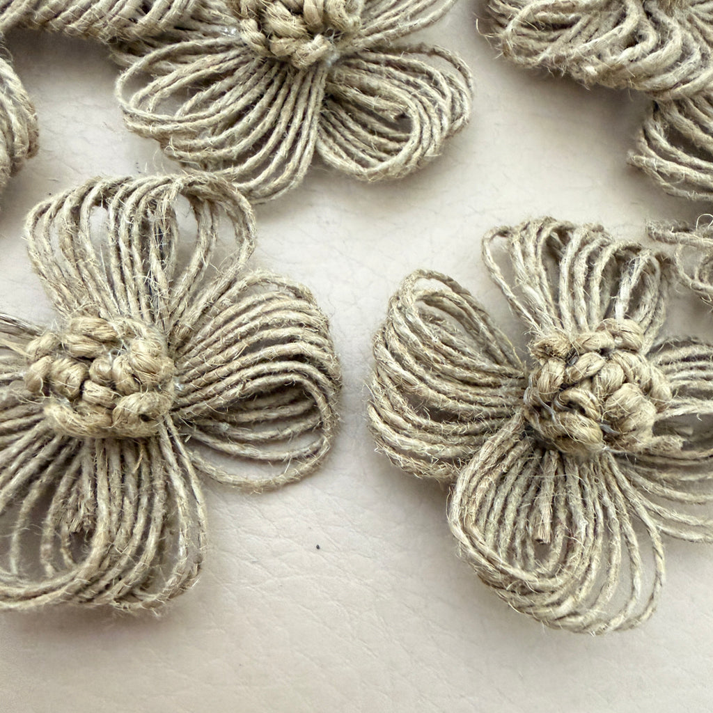 Close-up of two jute twine flower patches showing looped petal and knotted centre detail