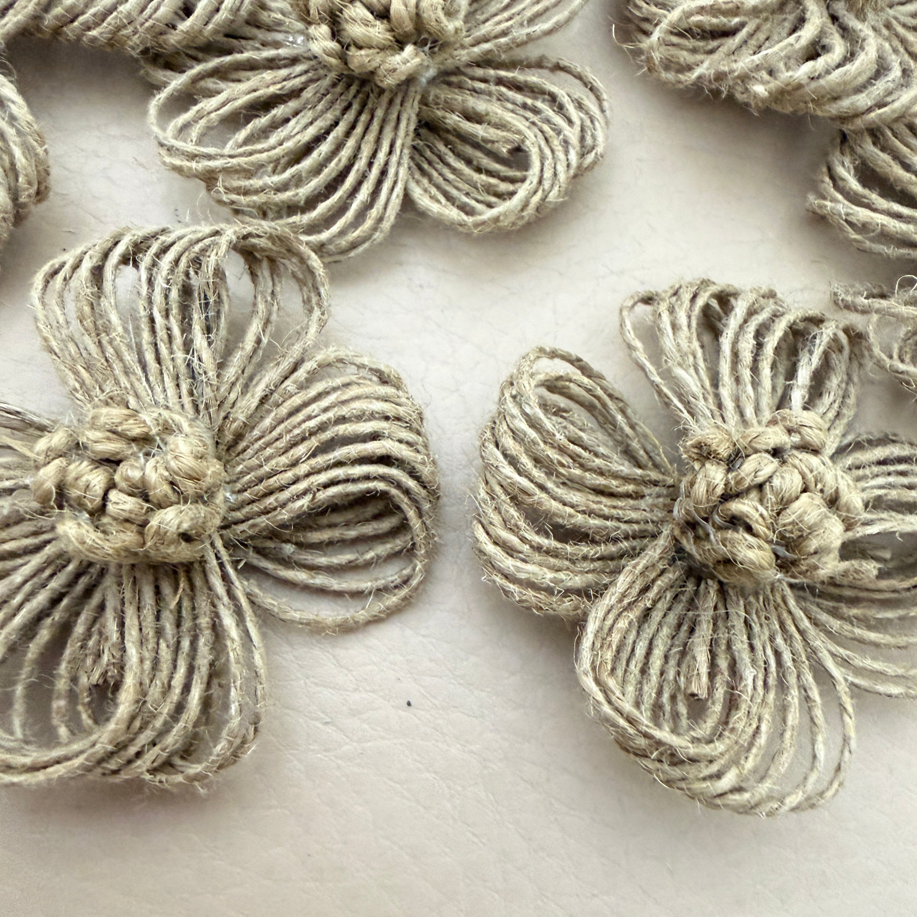 Close-up of two jute twine flower patches showing looped petal and knotted centre detail