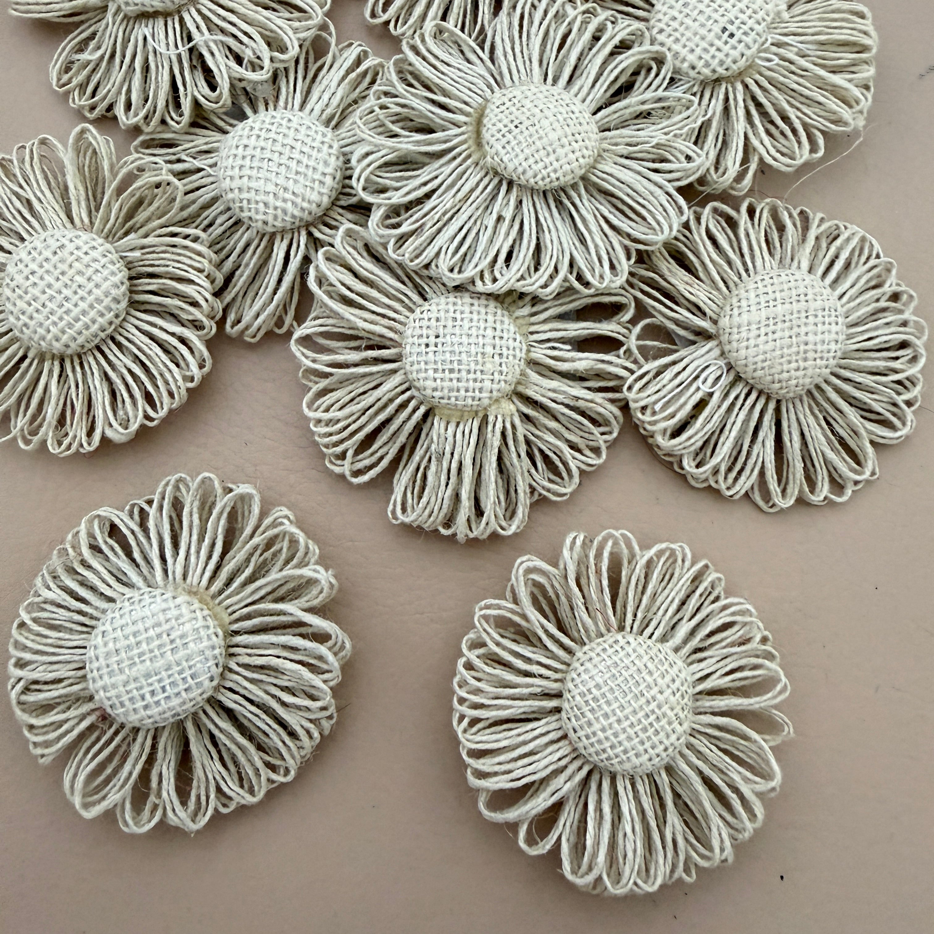 Pack of jute twine daisy flower patches spread on grey background