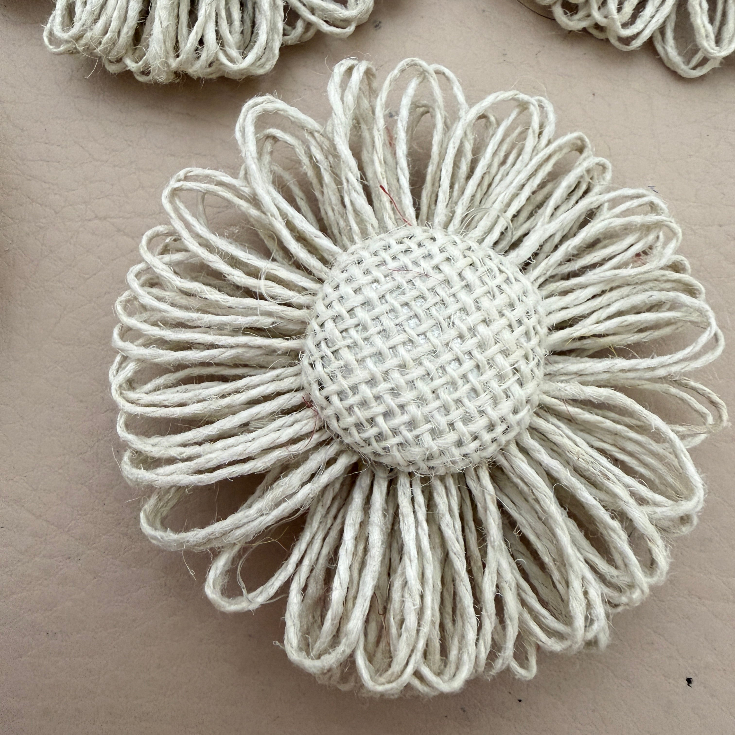 Close-up of single jute twine daisy showing looped petals and woven burlap dome centre