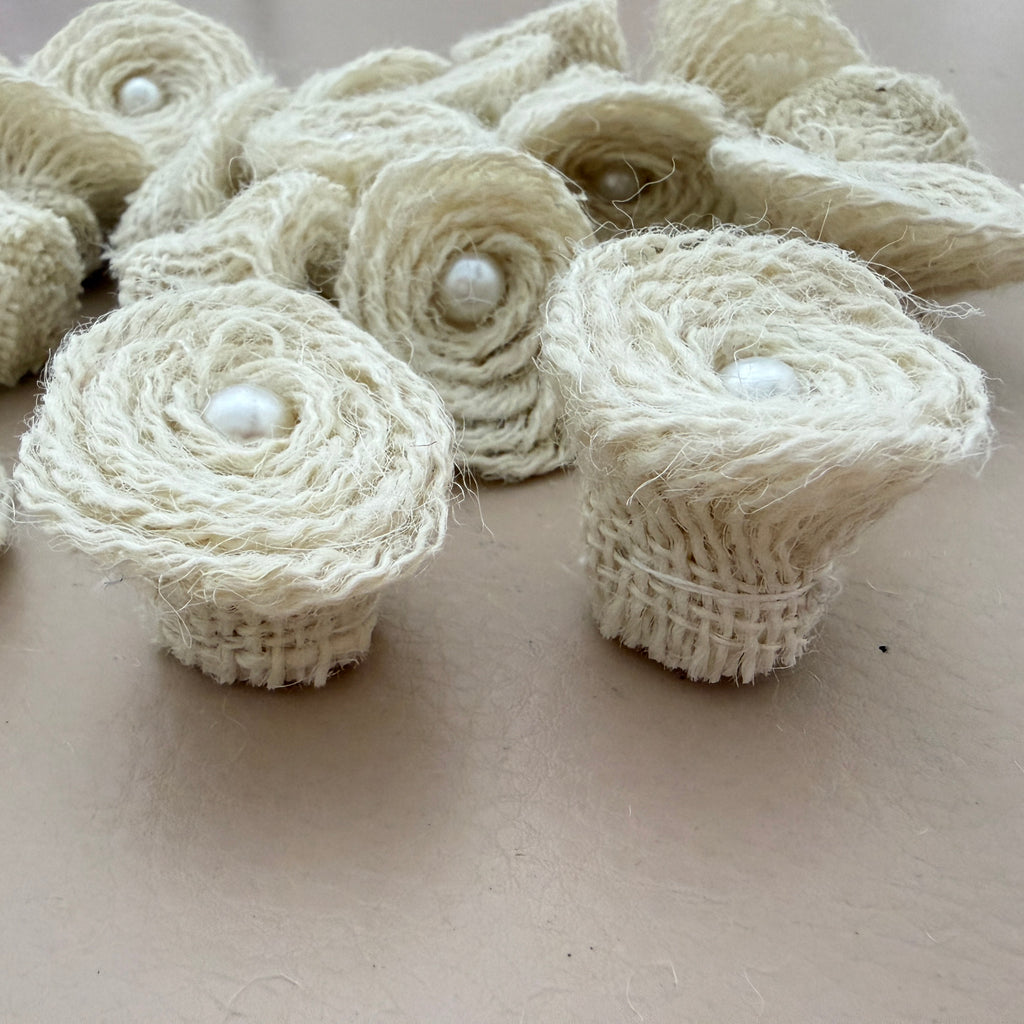 Close-up of two jute rope rosette patches showing spiral coil and pearl centre detail