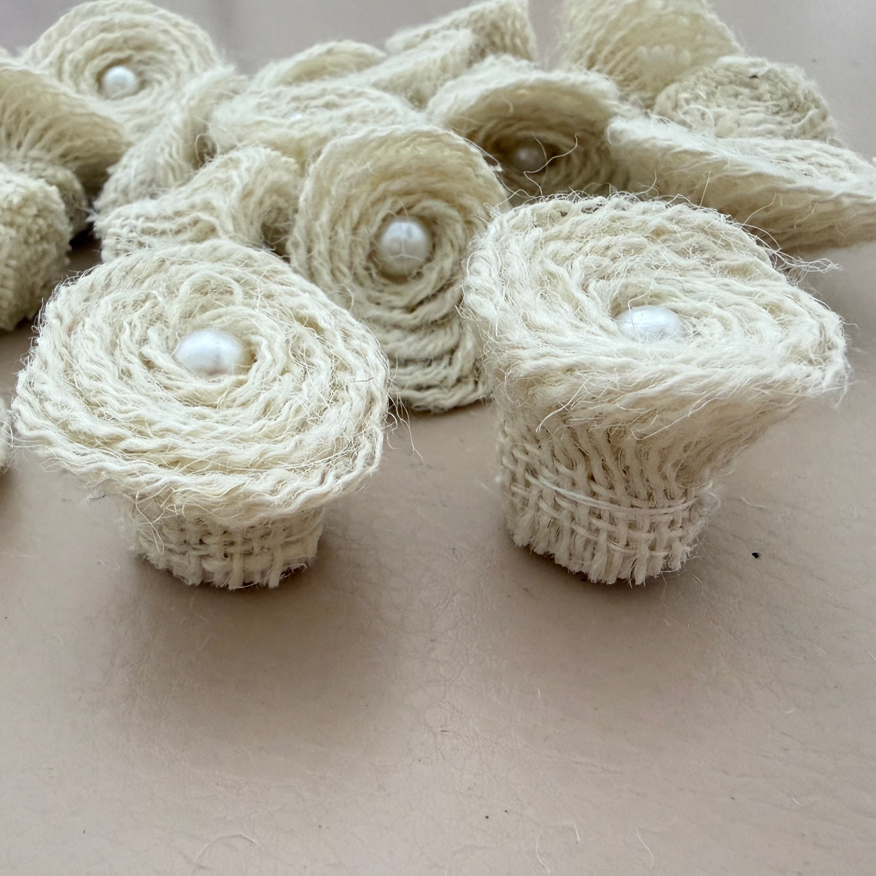 Close-up of two jute rope rosette patches showing spiral coil and pearl centre detail