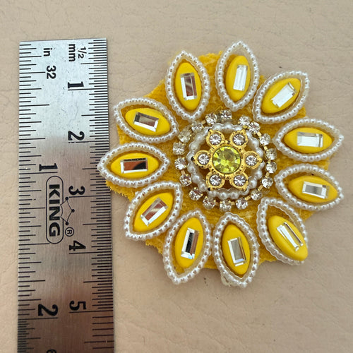 Handcrafted yellow floral patch held in hand showing size