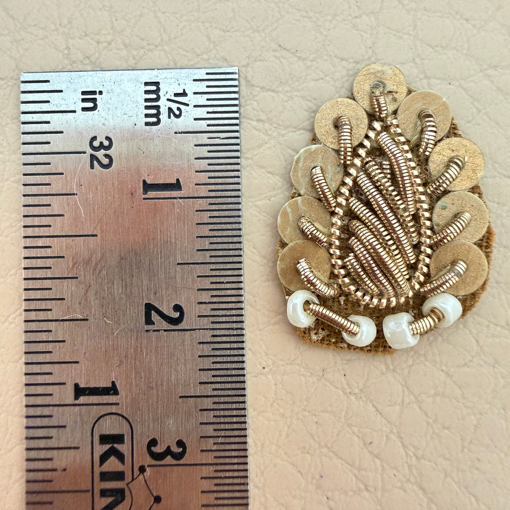 Gold zardozi patch held in hand for scale