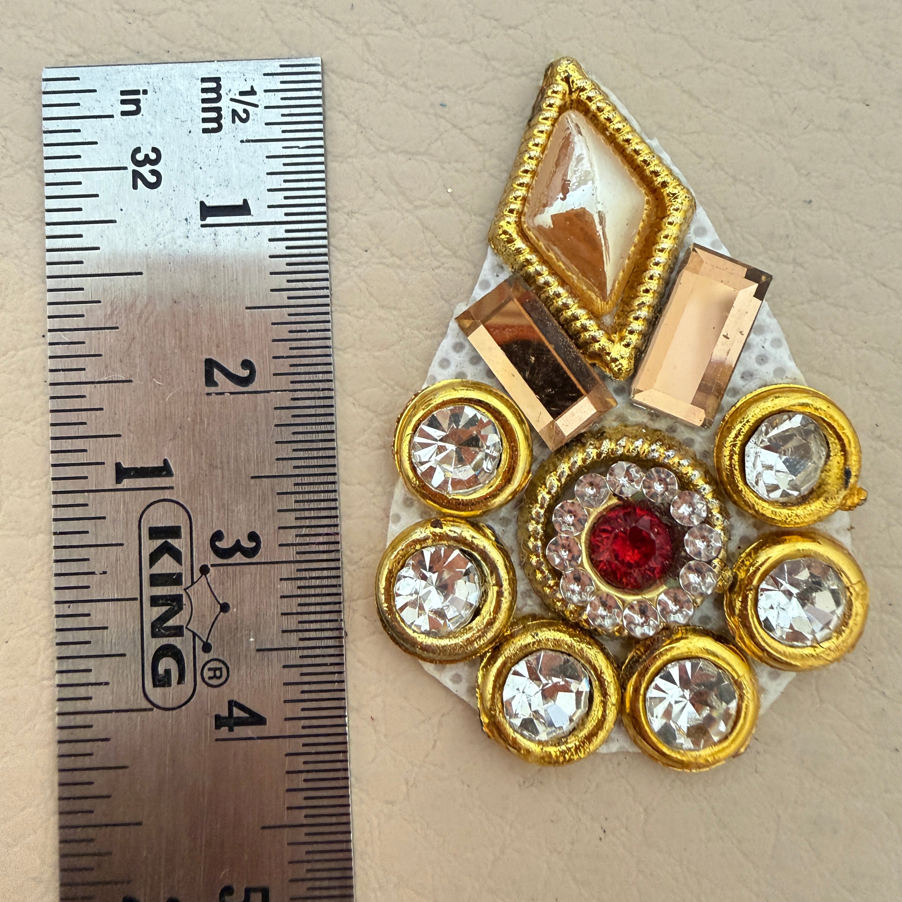 Hand holding a gold rhinestone patch to show size