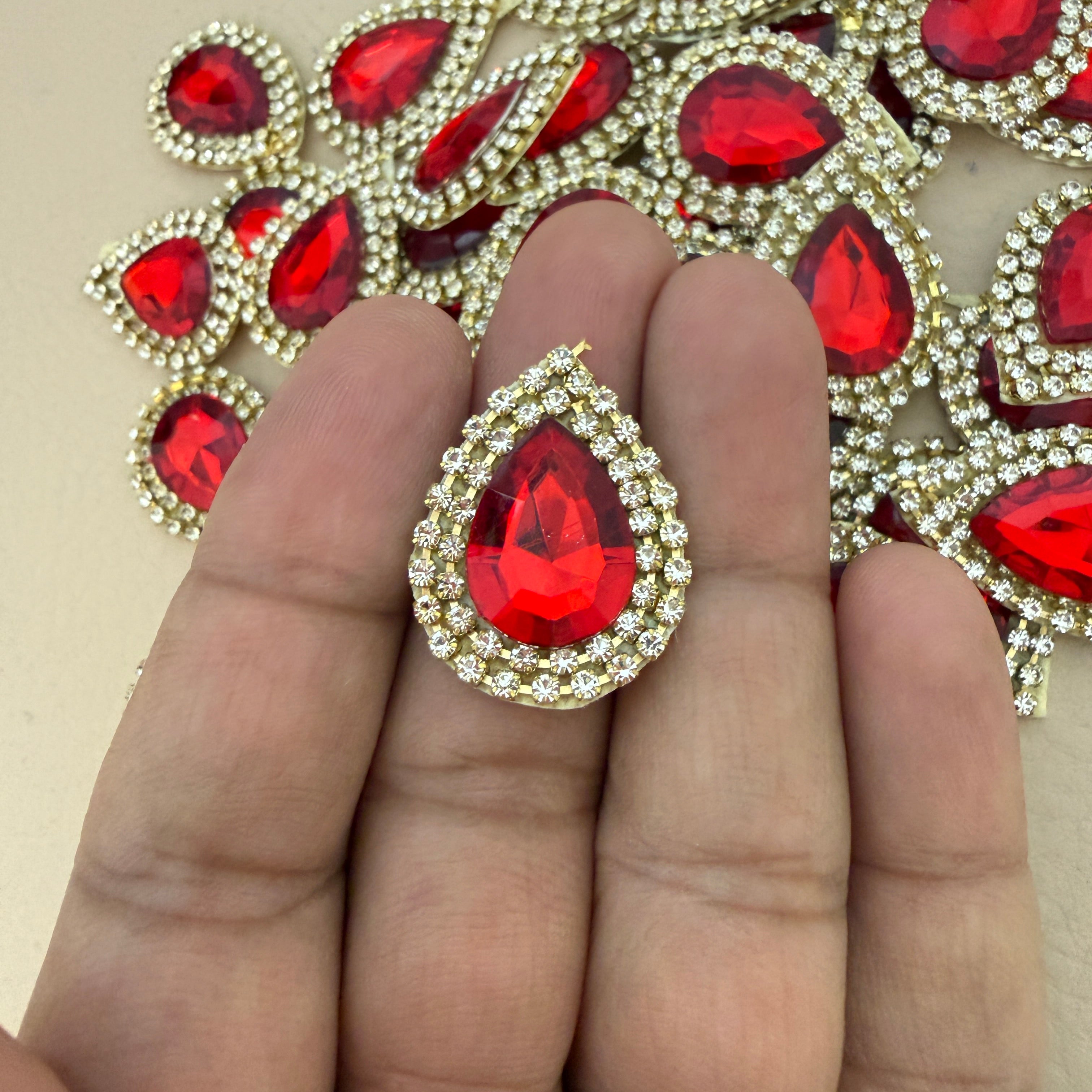 Red teardrop rhinestone patch held in hand showing size