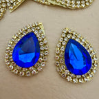 Close-up of two royal blue teardrop patches showing crystal and rhinestone detail