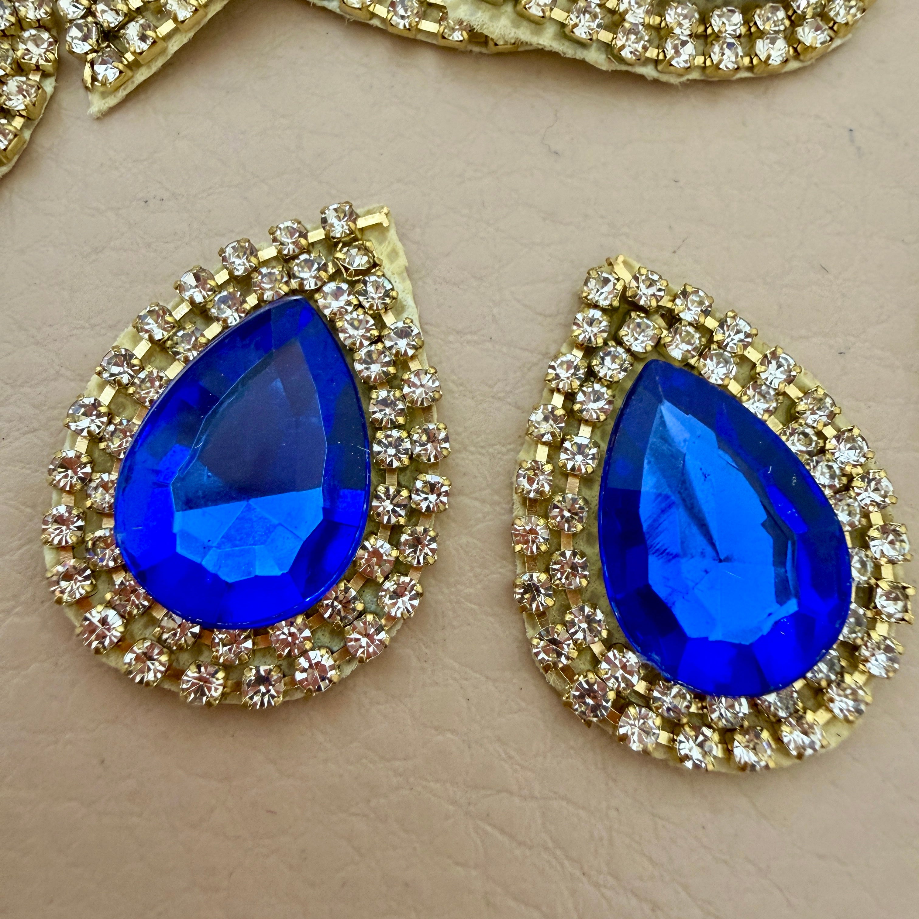 Close-up of two royal blue teardrop patches showing crystal and rhinestone detail