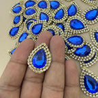 Single royal blue teardrop patch held in hand showing size reference