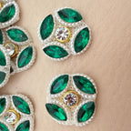 Close-up of emerald green rhinestone flower patch showing marquise stones and pearl border