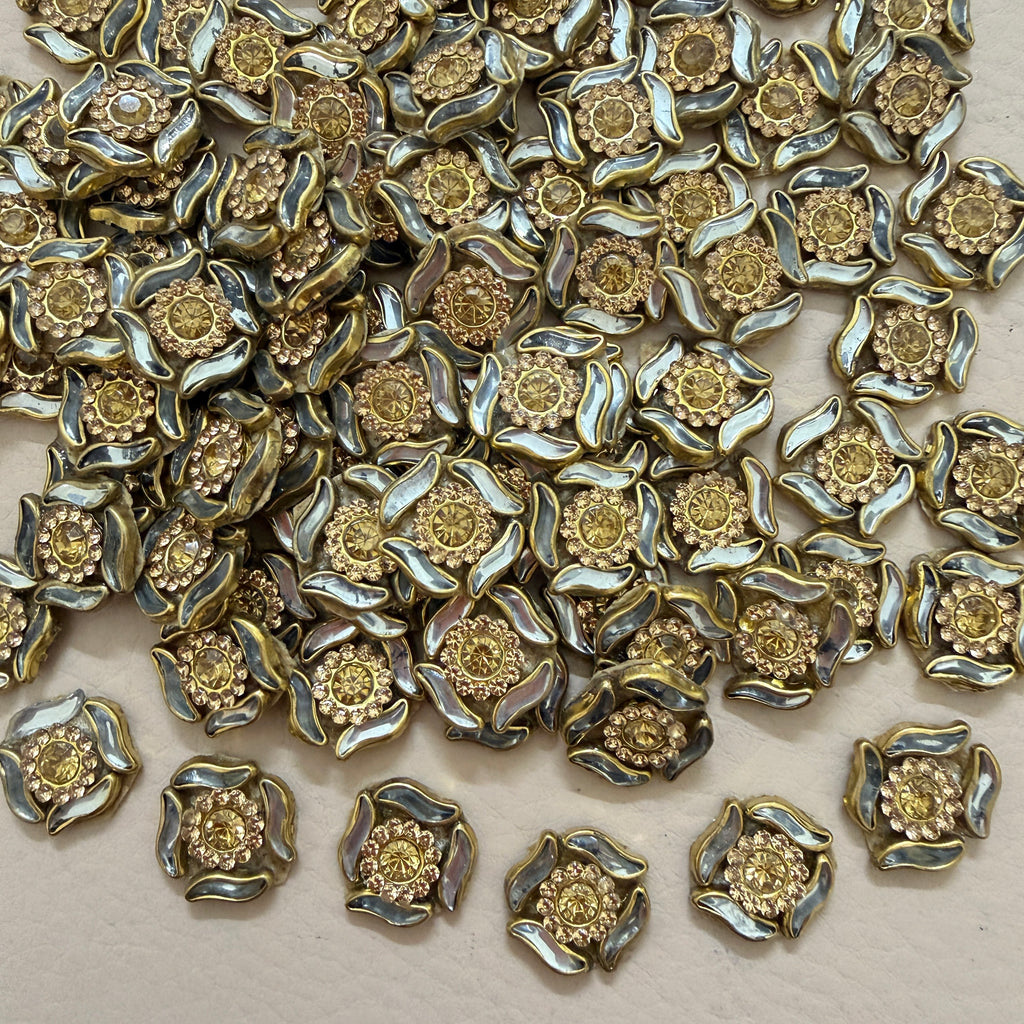 Antique gold rhinestone flower motif patch held in hand showing size
