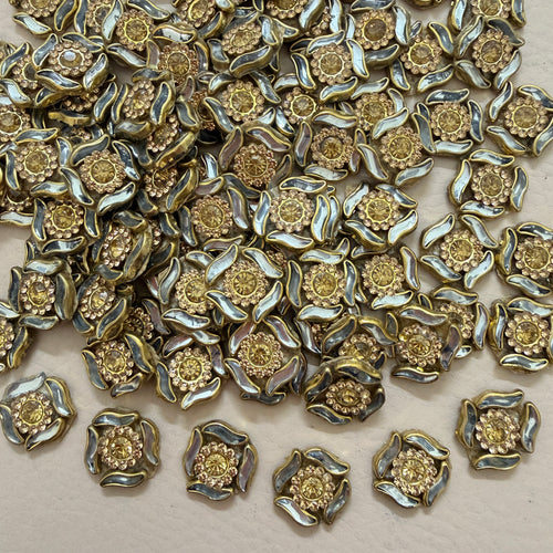 Antique gold rhinestone flower motif patch held in hand showing size