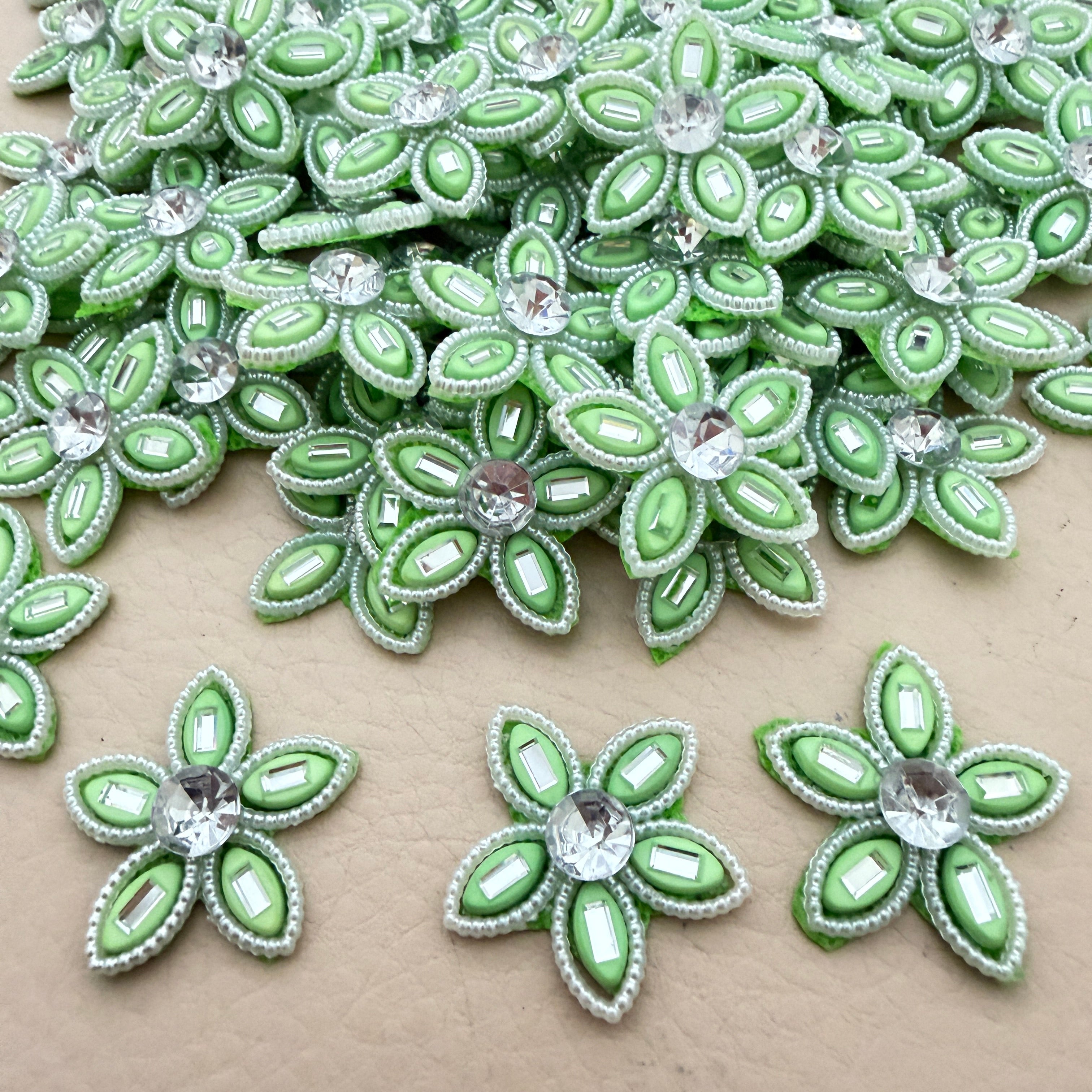 Bulk lot of mint green rhinestone flower motif patches spread out on surface