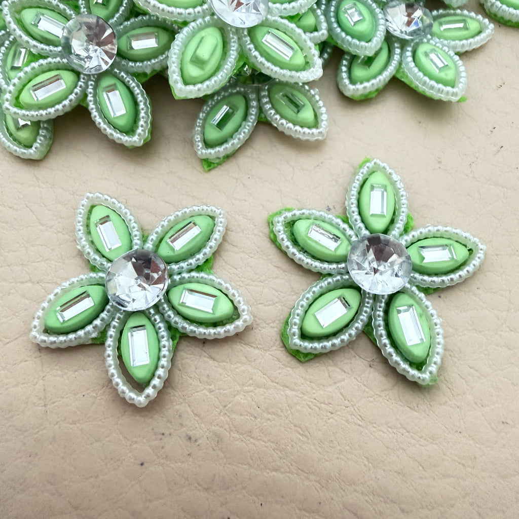 Two mint green rhinestone flower motif patches showing front detail up close
