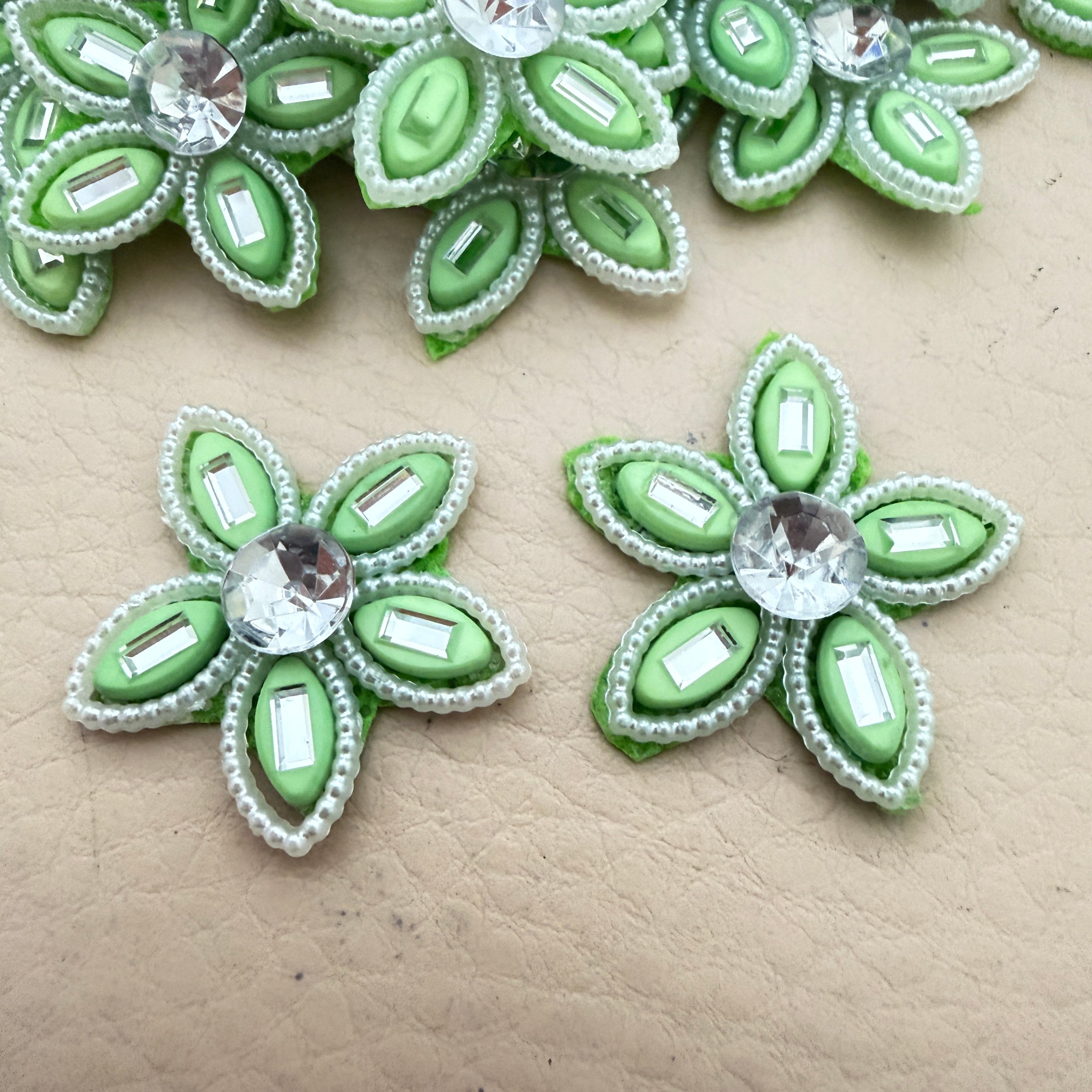 Two mint green rhinestone flower motif patches showing front detail up close
