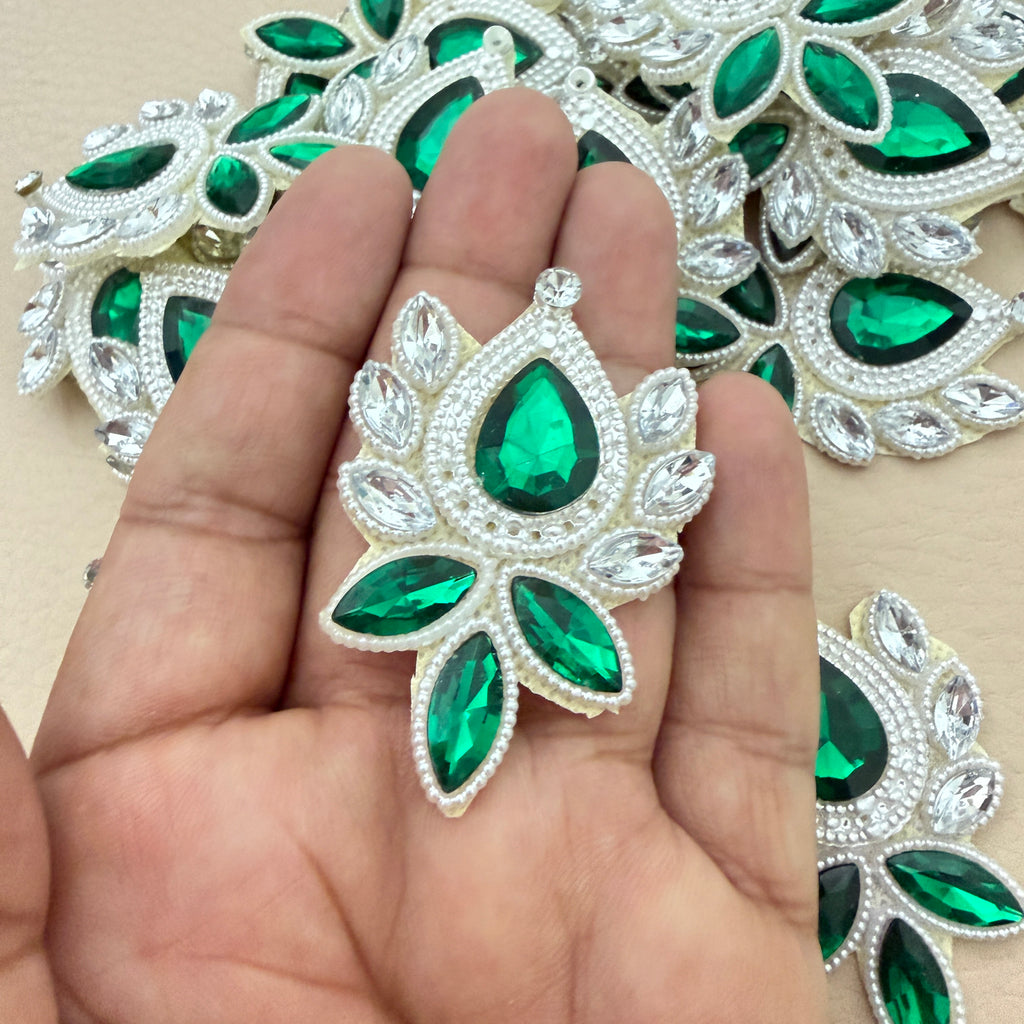 Hand holding emerald rhinestone patch for size reference
