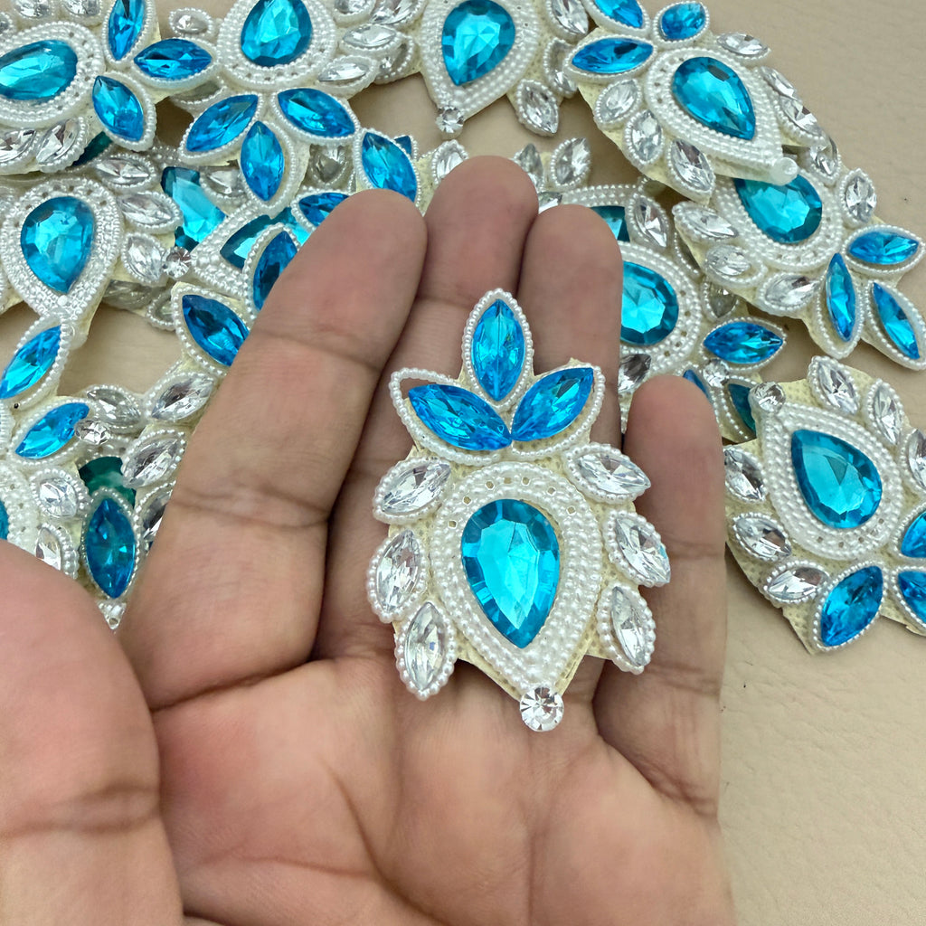 Hand holding sky blue rhinestone patch for size reference