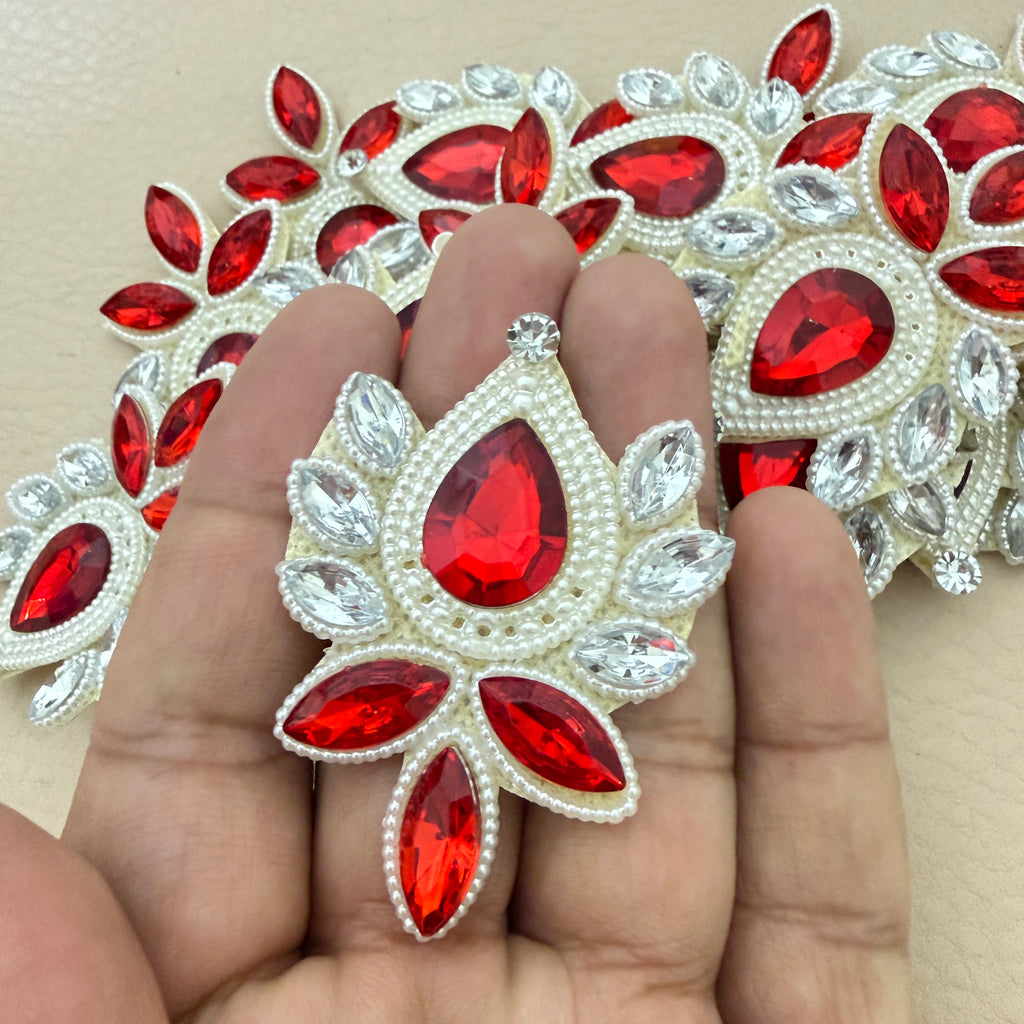 Hand holding ruby red rhinestone patch for size reference