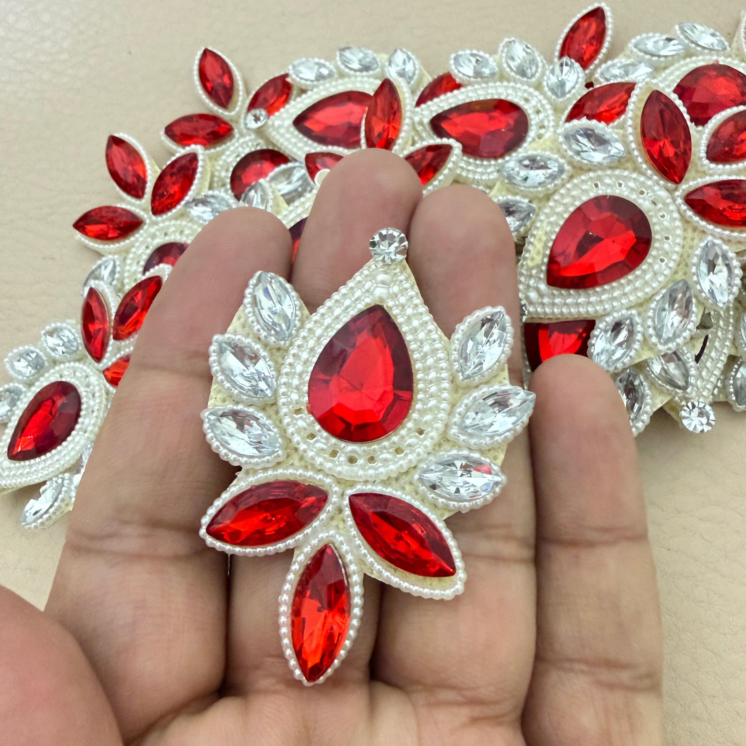 Hand holding ruby red rhinestone patch for size reference