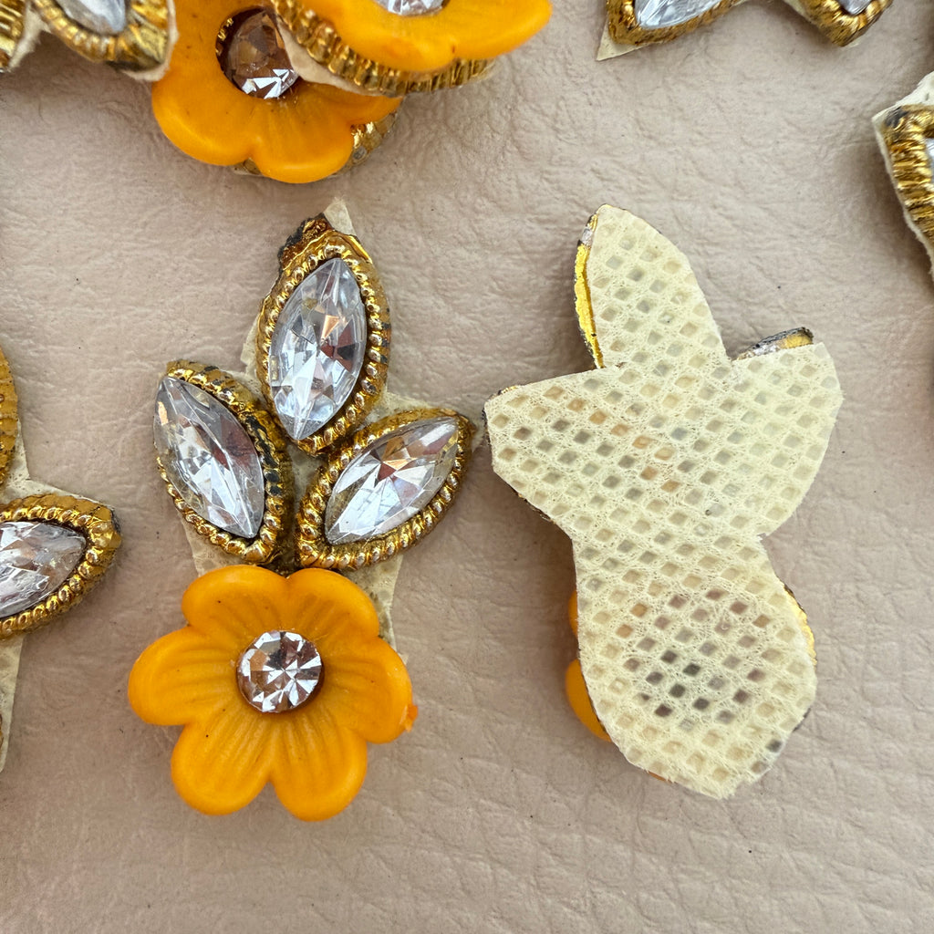 Close-up of yellow flower and clear rhinestone leaf patches