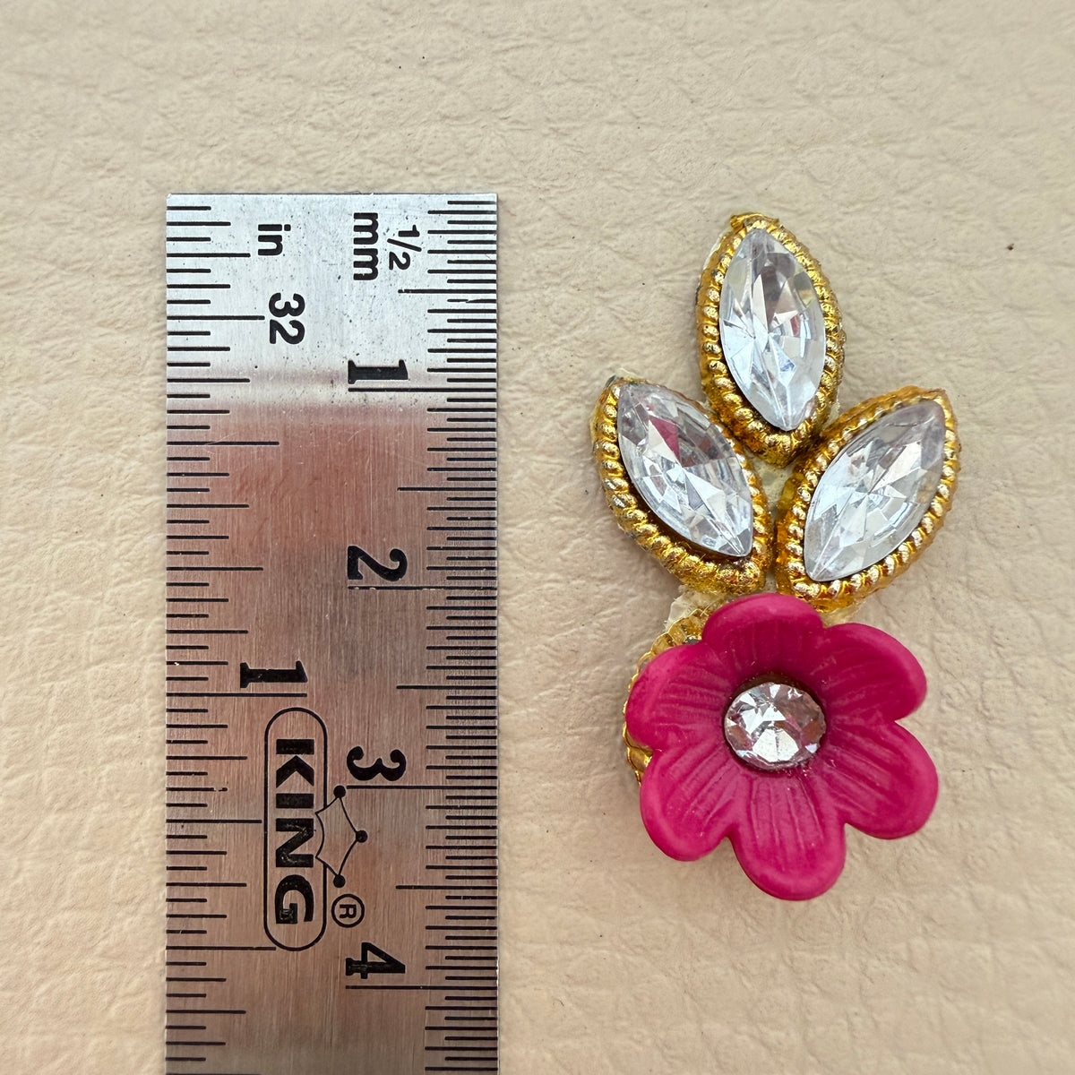 Pink flower and leaf applique patch placed beside a ruler for size reference