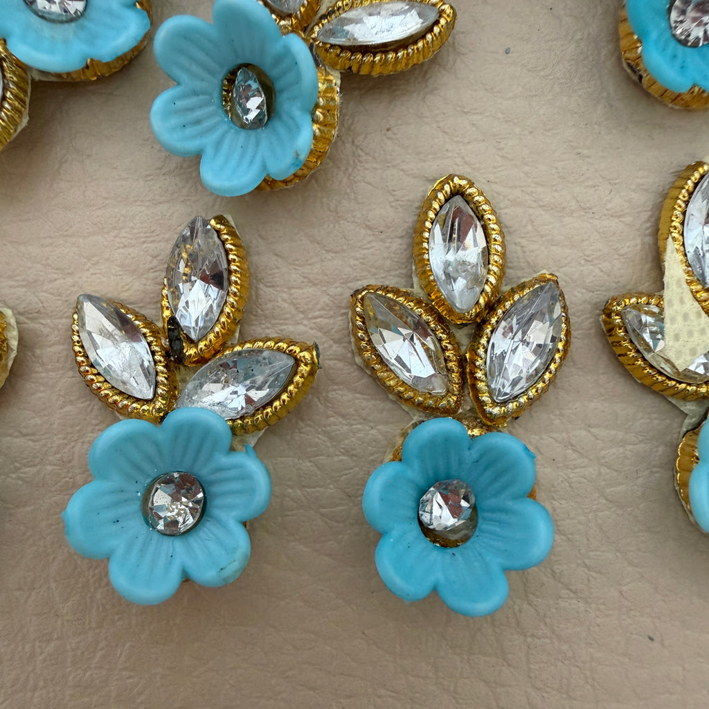 Sky blue flower and leaf embellishment patch held in hand to show its compact size