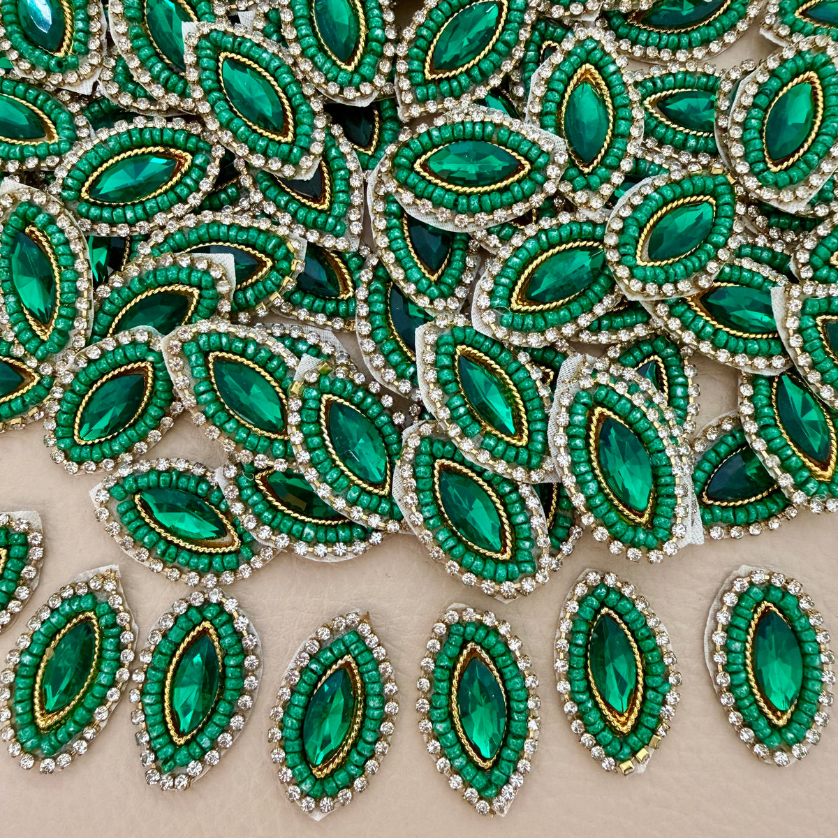 Emerald green marquise crystal patch with green beadwork, clear rhinestones, gold-tone detailing, and ivory mesh backing