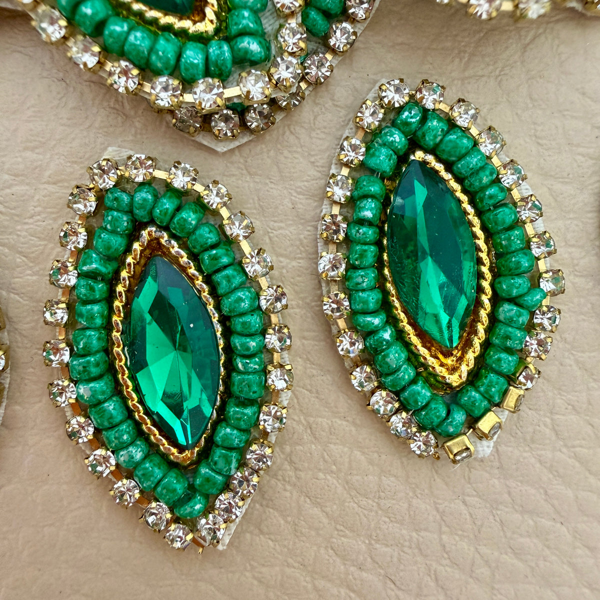 Emerald green crystal and pearl rhinestone patch held in hand to show its size and detailed beadwork