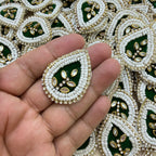 Close-up of two bottle green kundan teardrop patches with white beads
