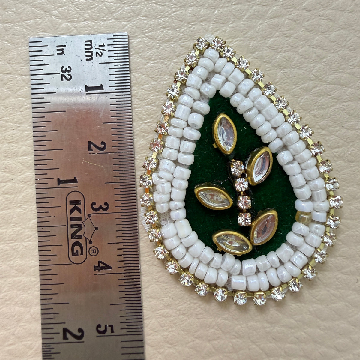 Bottle green kundan teardrop patch held in hand