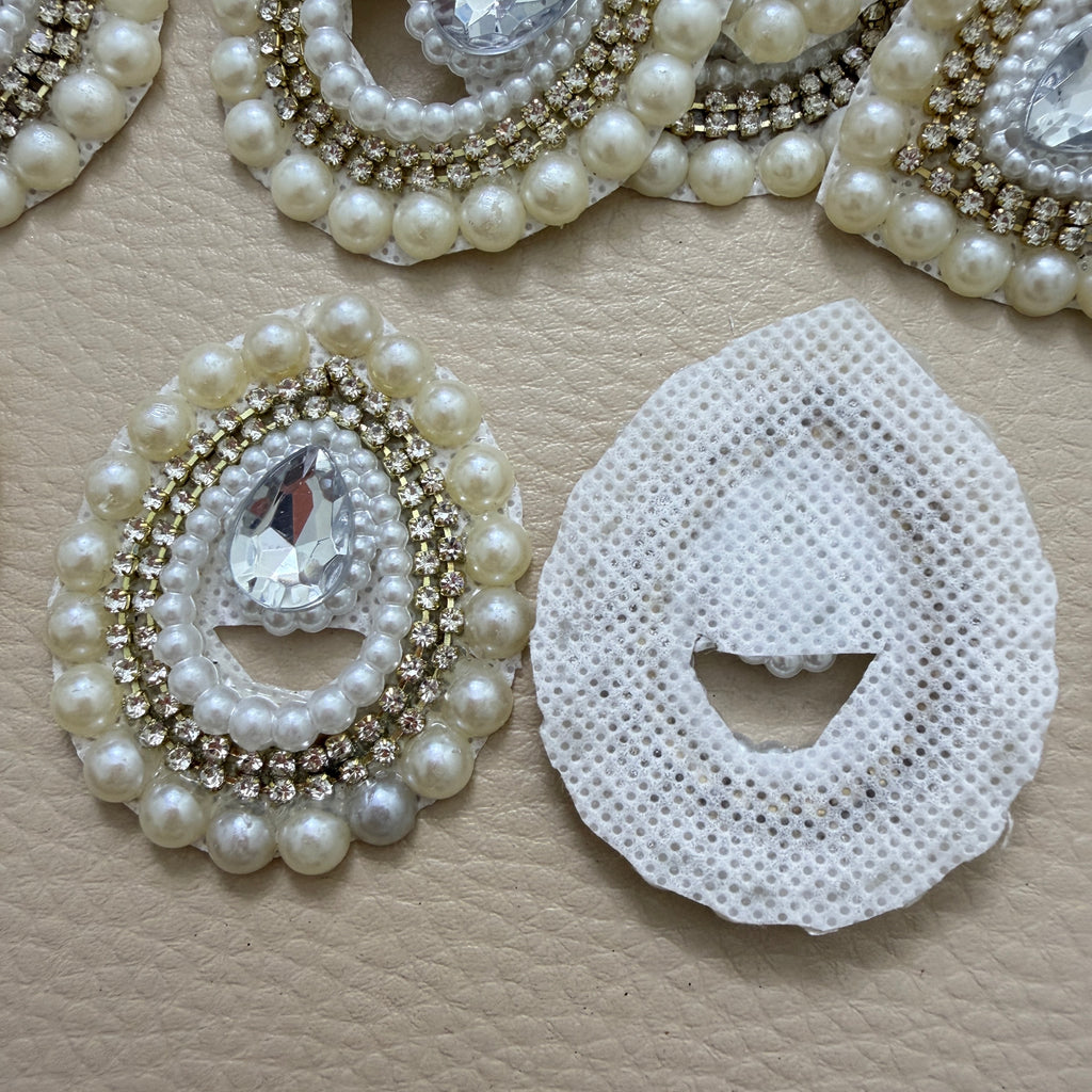 Two ivory pearl and clear rhinestone teardrop patches close-up