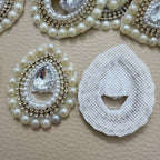 Two ivory pearl and clear rhinestone teardrop patches close-up