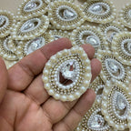 Pearl-bordered teardrop rhinestone patch held in hand for scale
