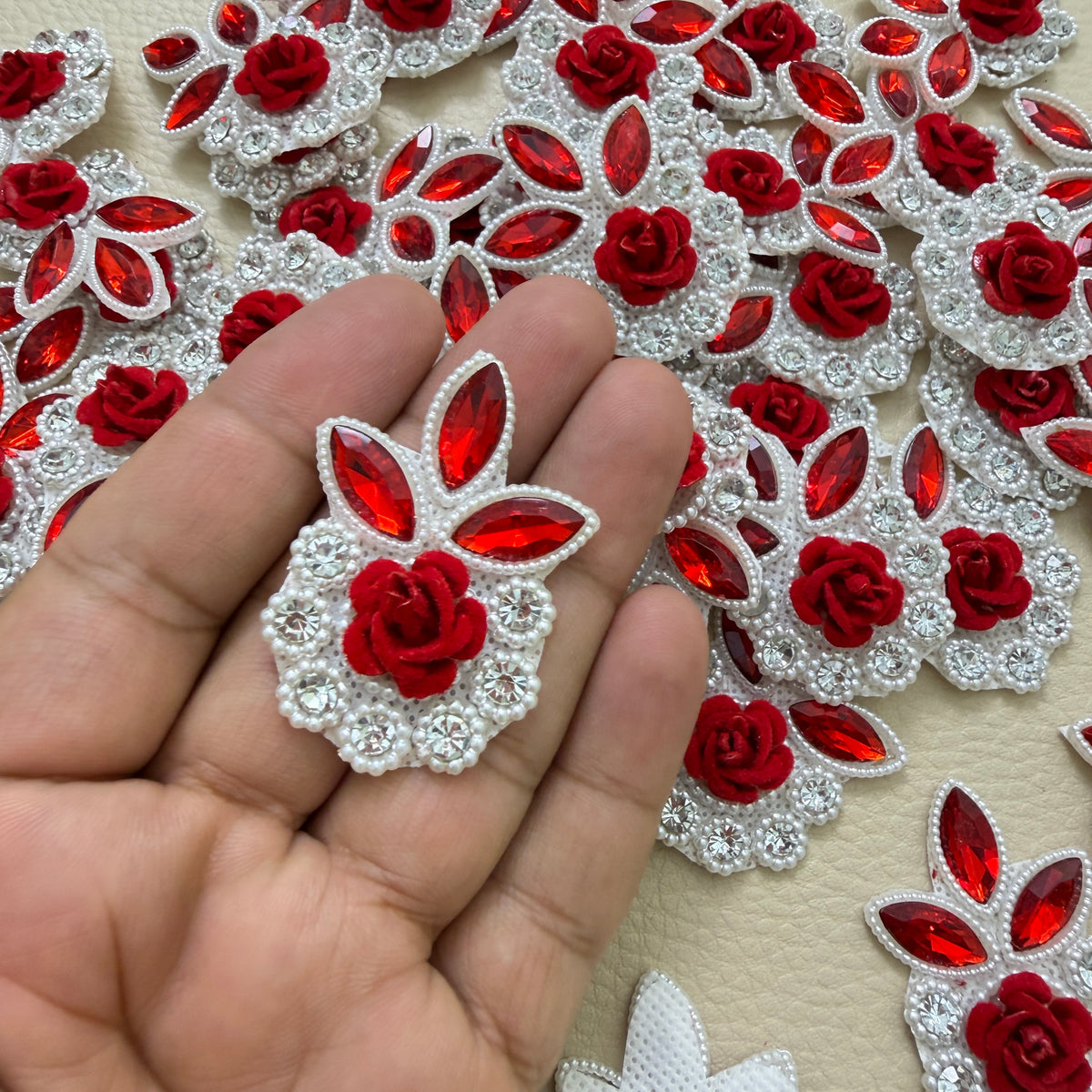 Red rose rhinestone patch held in hand to show its scale
