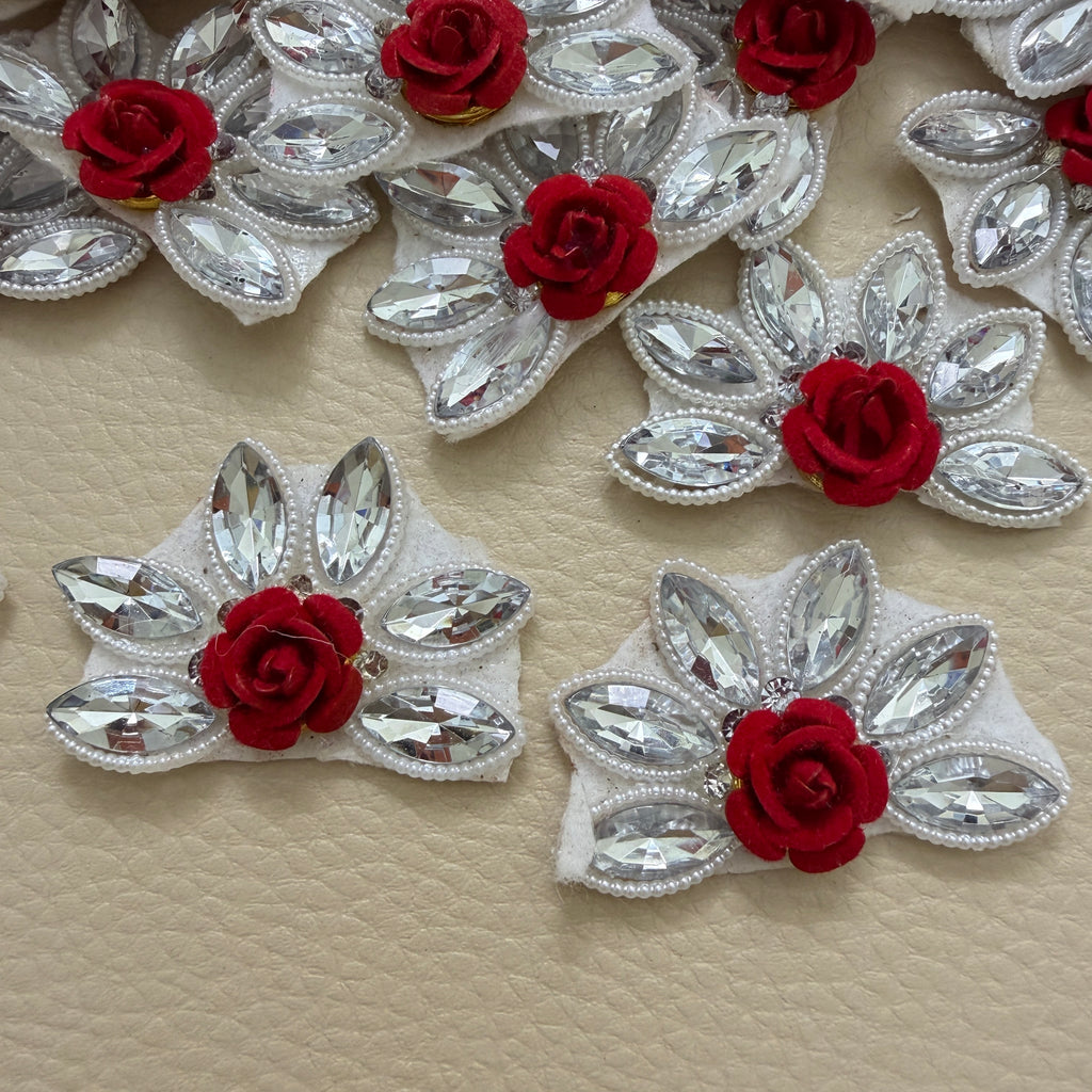 Maroon rose and clear marquise rhinestone flower patches arranged on a beige surface