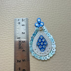 Blue teardrop applique patch held in a hand for scale