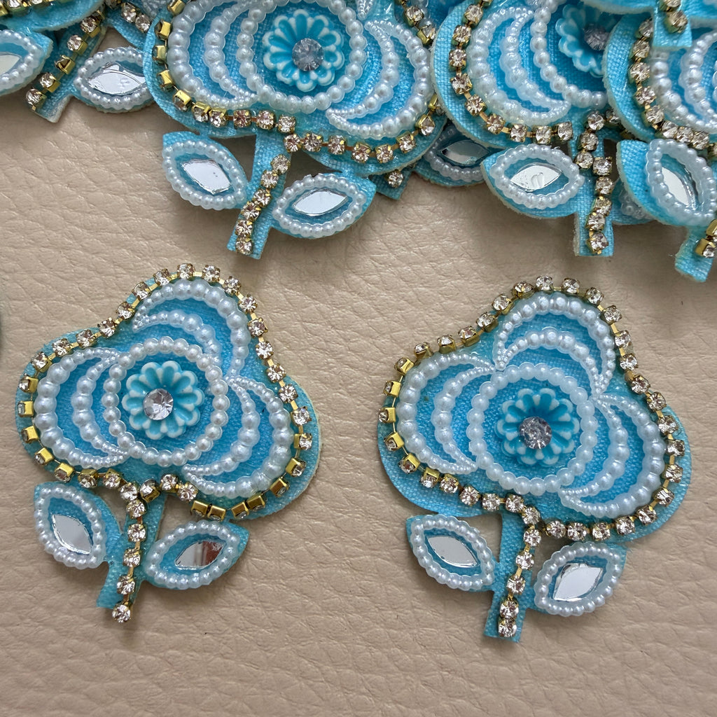 Sky blue embellished flower patch held in a hand for scale