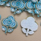 Sky blue floral applique patch beside a ruler for size reference