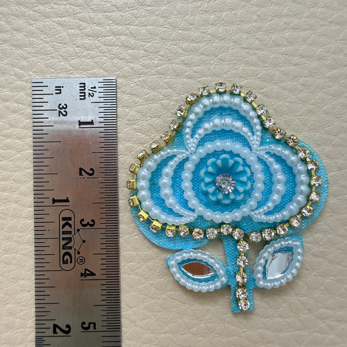Front and white fabric backing of sky blue floral applique patch