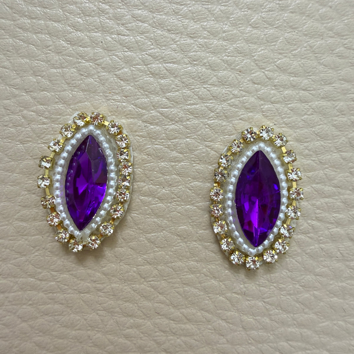 Purple stone and pearl-look patch beside a ruler for size reference