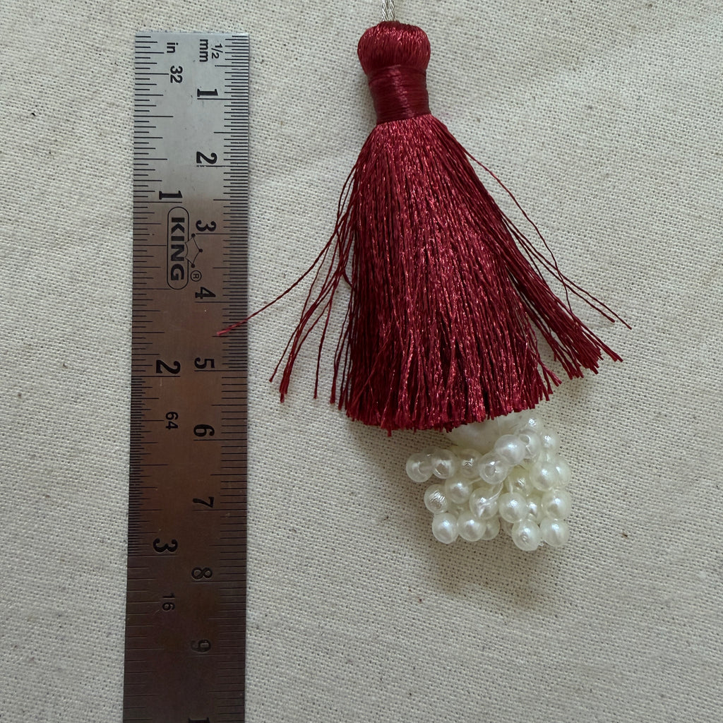 Single maroon silk tassel with pearl cluster next to ruler showing approx 10cm length