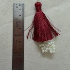 Single maroon silk tassel with pearl cluster next to ruler showing approx 10cm length