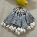 Multiple silver silk tassels with cowrie shells fanned out on fabric