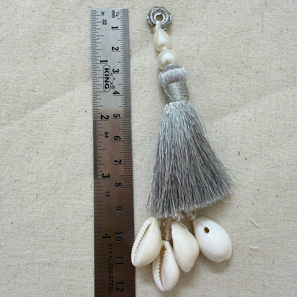 Single silver silk tassel with cowrie shells next to ruler showing approx 12cm length