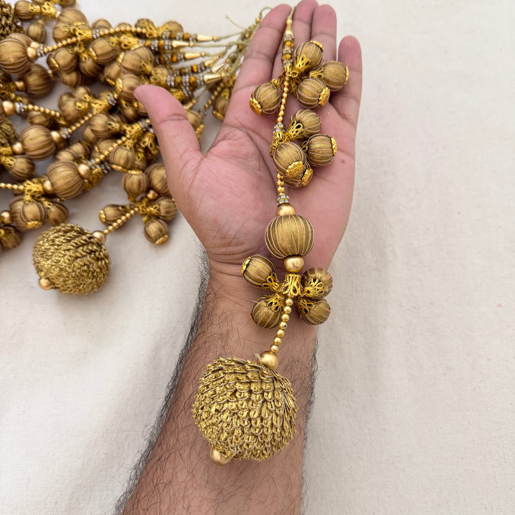 Gold Thread Ball Latkan held in hand showing size and cascading detail