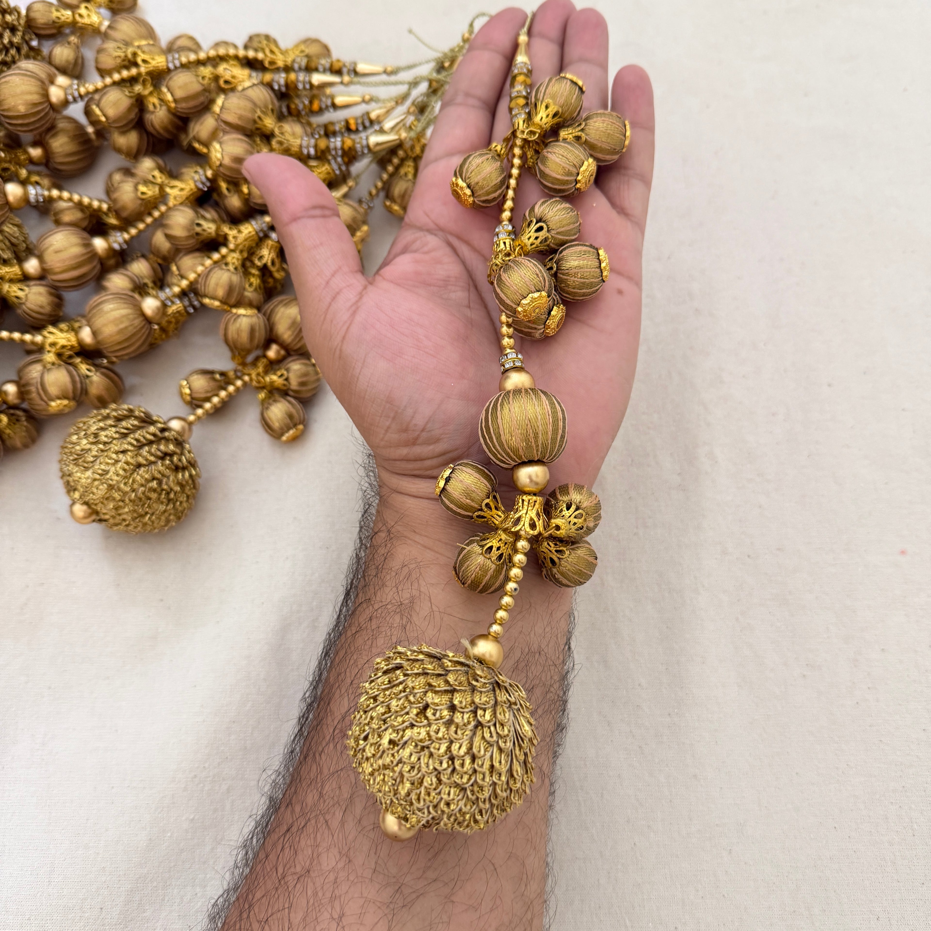 Gold Thread Ball Latkan held in hand showing size and cascading detail