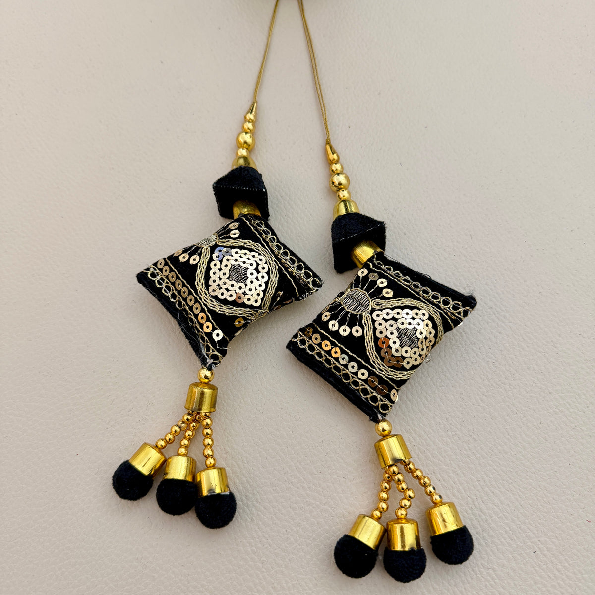 Pair of black and gold embroidered cushion latkan tassels with sequins and three pom-pom drops each